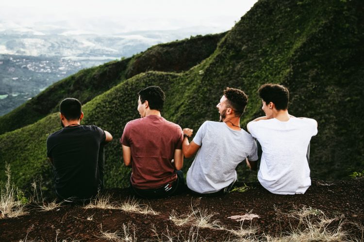 A group of men hanging out on a cliff having fun 